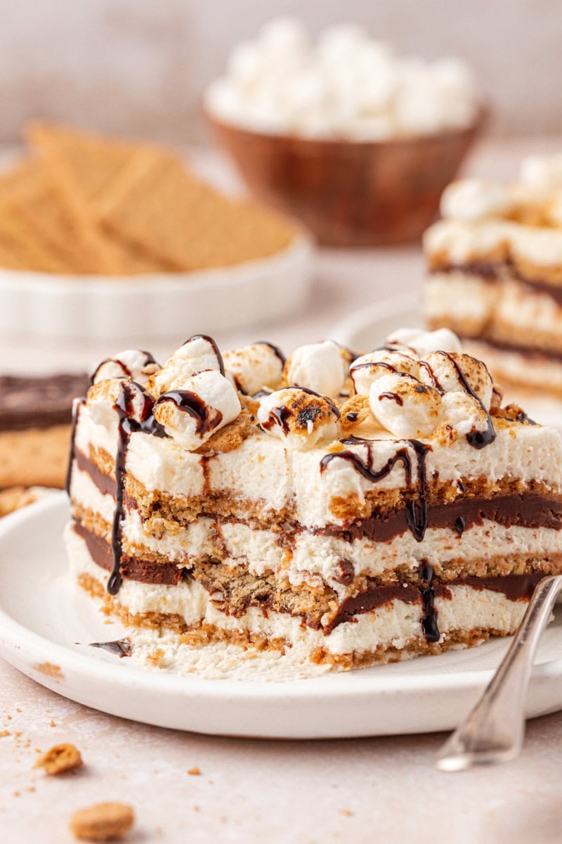 slice of s'mores icebox cake with layers of graham crackers, marshmallow filling, and chocolate ganache