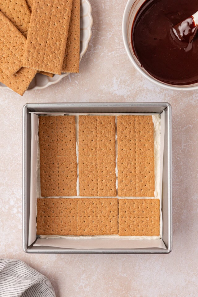 graham crackers arranged in a single layer over a thin layer of marshmallow filling in a square pan