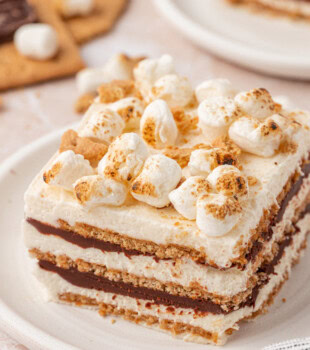 close up of a slice of s'mores icebox cake, showing layers of marshmallow filling, chocolate ganache, and graham crackers