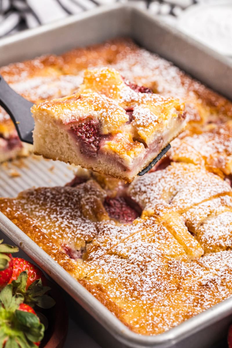a serving of strawberry cheesecake cobbler being lifted away from the remaining cobbler