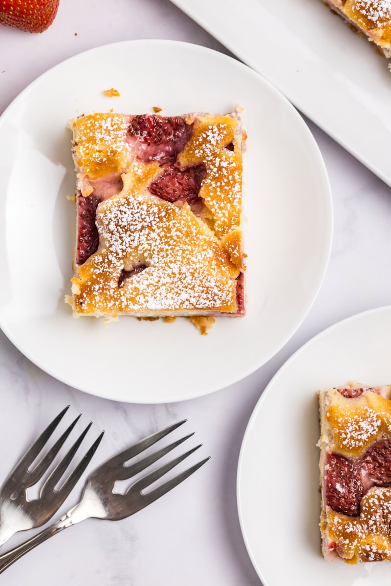 overhead view of strawberry cheesecake cobbler served on white plates