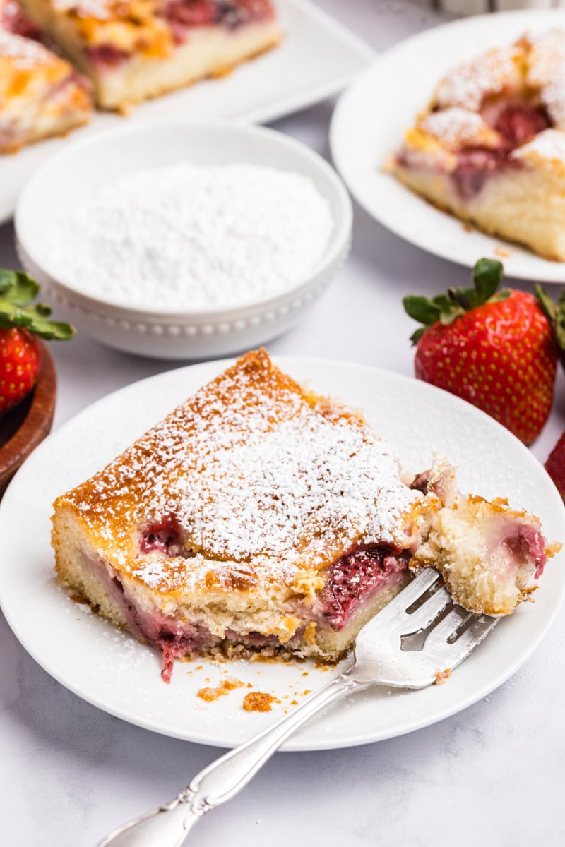 a slice of strawberry cheesecake cobbler topped with powdered sugar