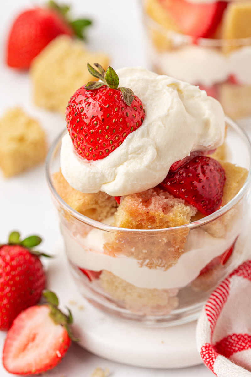 close up of a strawberry shortcake jar, featuring layers of vanilla cake, macerated strawberries, and whipped cream
