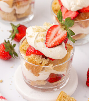 an individual strawberry shortcake jar topped made with layers of vanilla cake cubes, whipped cream, and strawberries