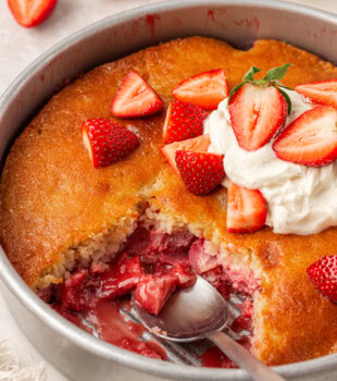 strawberry spoon cake with a scoop missing to show the juicy strawberry layer underneath a soft cake