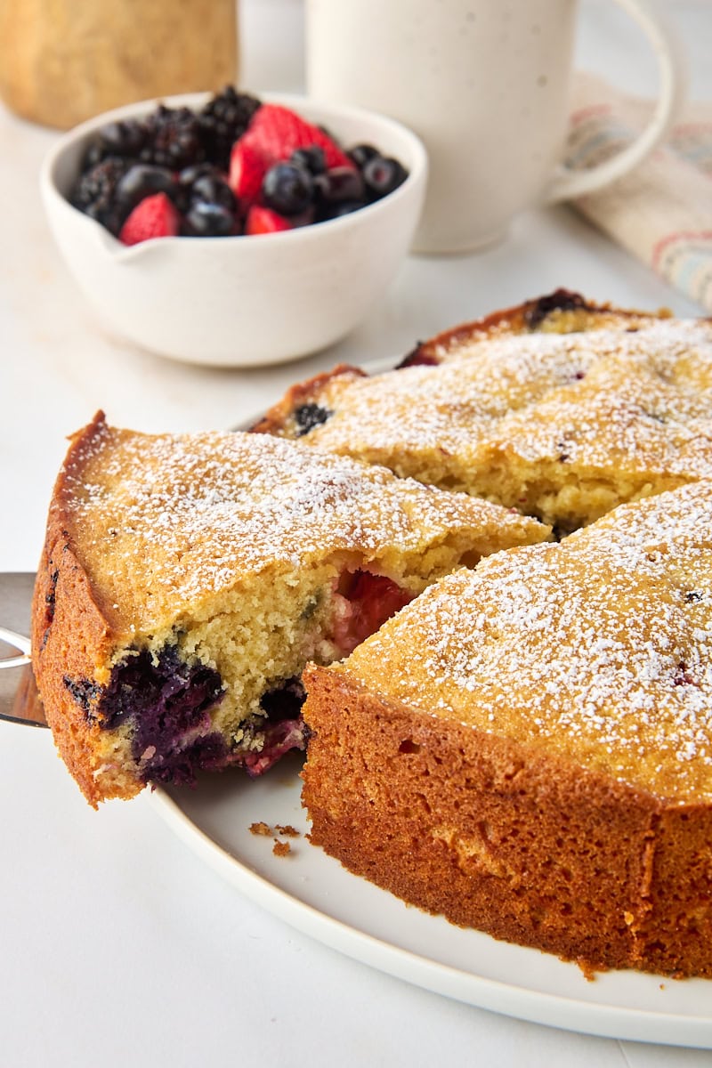 a slice of berry muffin cake on a cake server being removed from the remaining cake