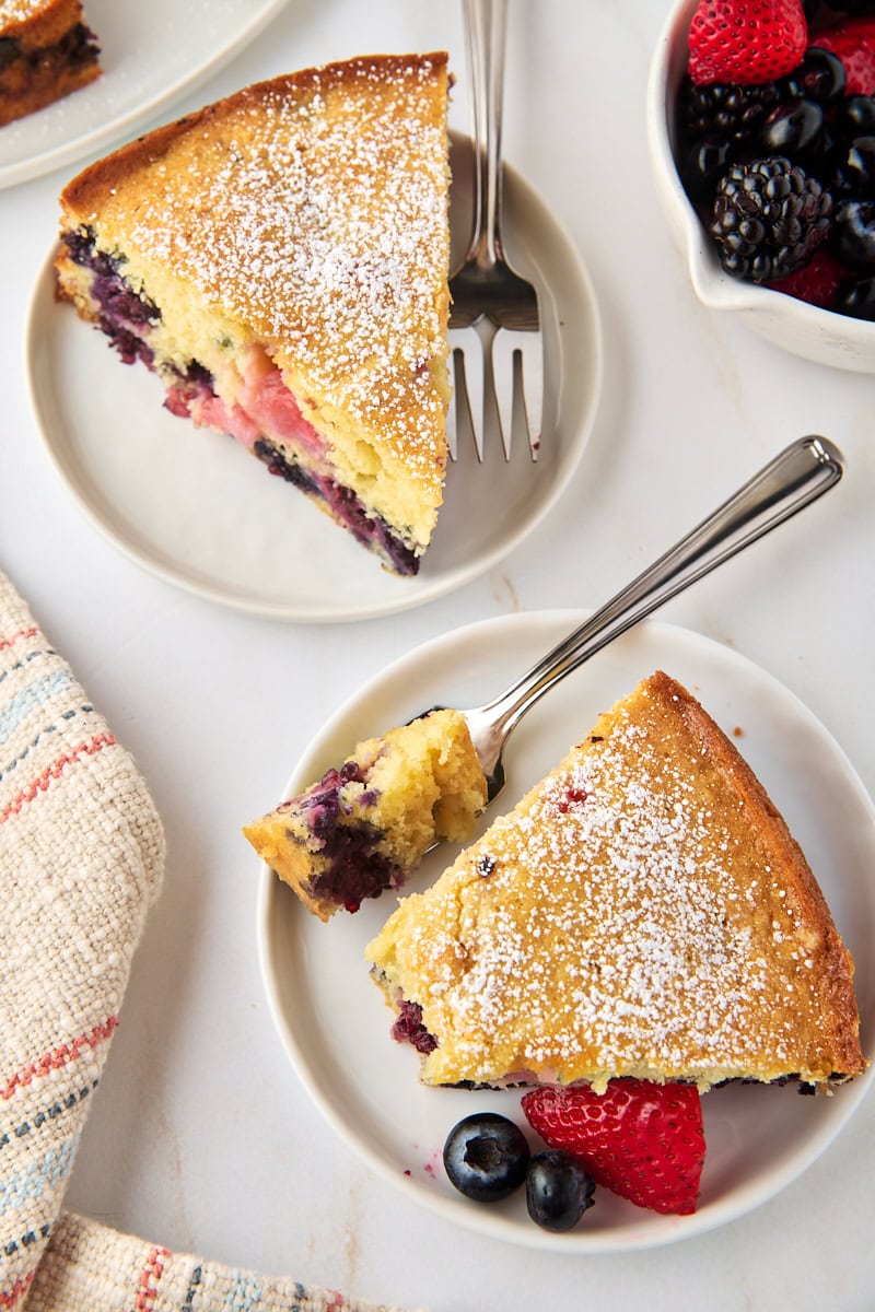 overhead view of two slices of berry muffin cake on white plates