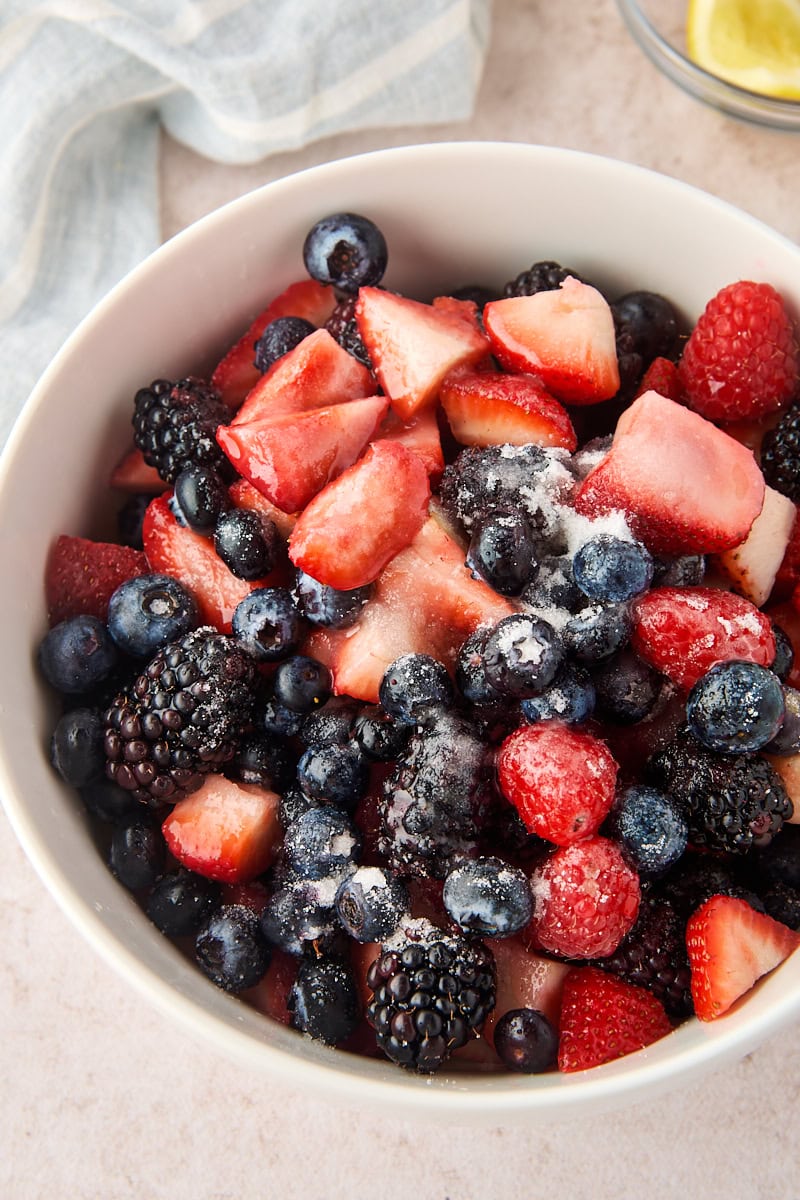 fresh mixed berries with sugar and lemon juice added before stirring to macerate