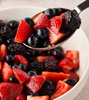 a spoonful of macerated berries scooped from a large bowl of berries