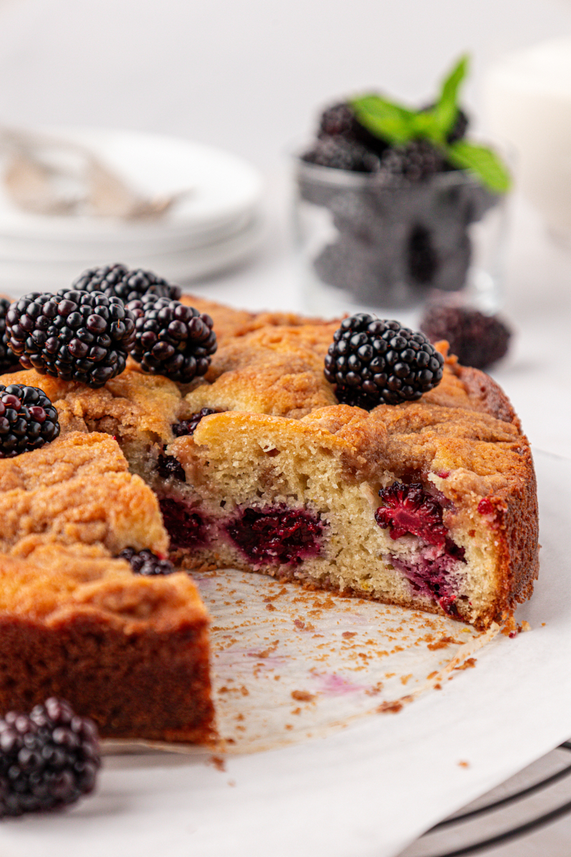partially sliced blackberry buckle with fresh berries and a chunky crumb topping