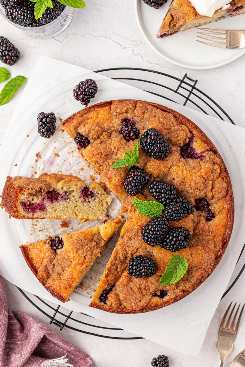 partially sliced blackberry buckle with plenty of berries and a chunky crumb topping