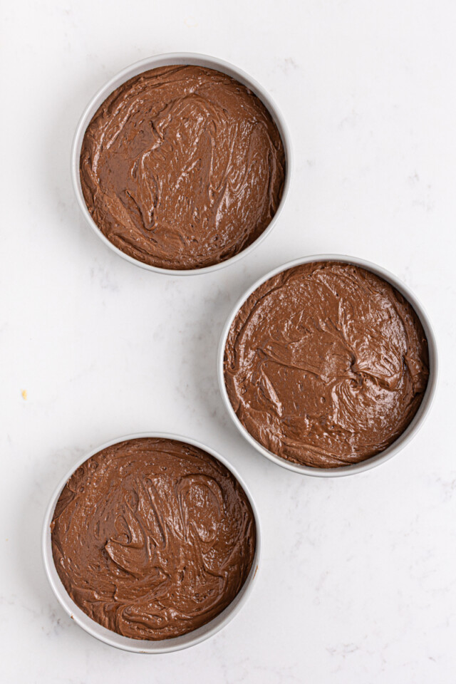overhead view of three chocolate cake layers in cake pans before going into the oven
