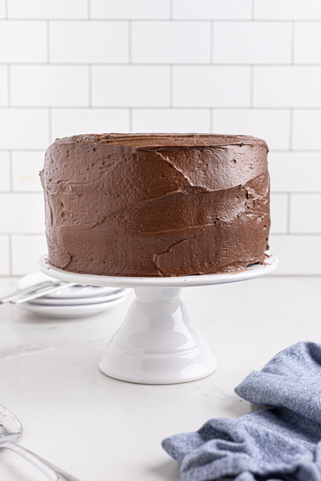 frosted chocolate layer cake on a white cake stand