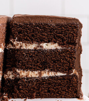 partially sliced chocolate cake with three layers of soft cake sandwiched around a tangy cream cheese filling and frosted with chocolate sour cream frosting