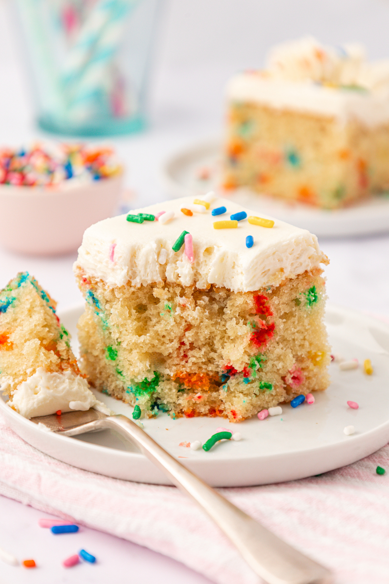 a slice of funfetti sheet cake filled with rainbow sprinkles and topped with vanilla frosting