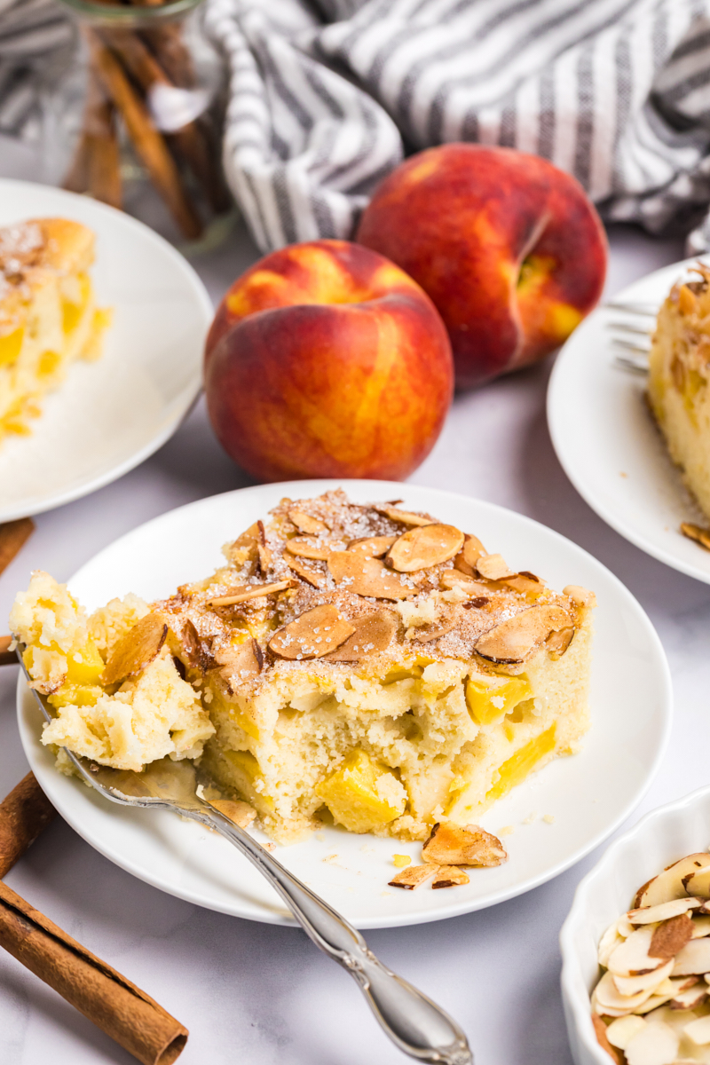 a slice of peach buckle filled with fresh peaches and topped with cinnamon-almond topping