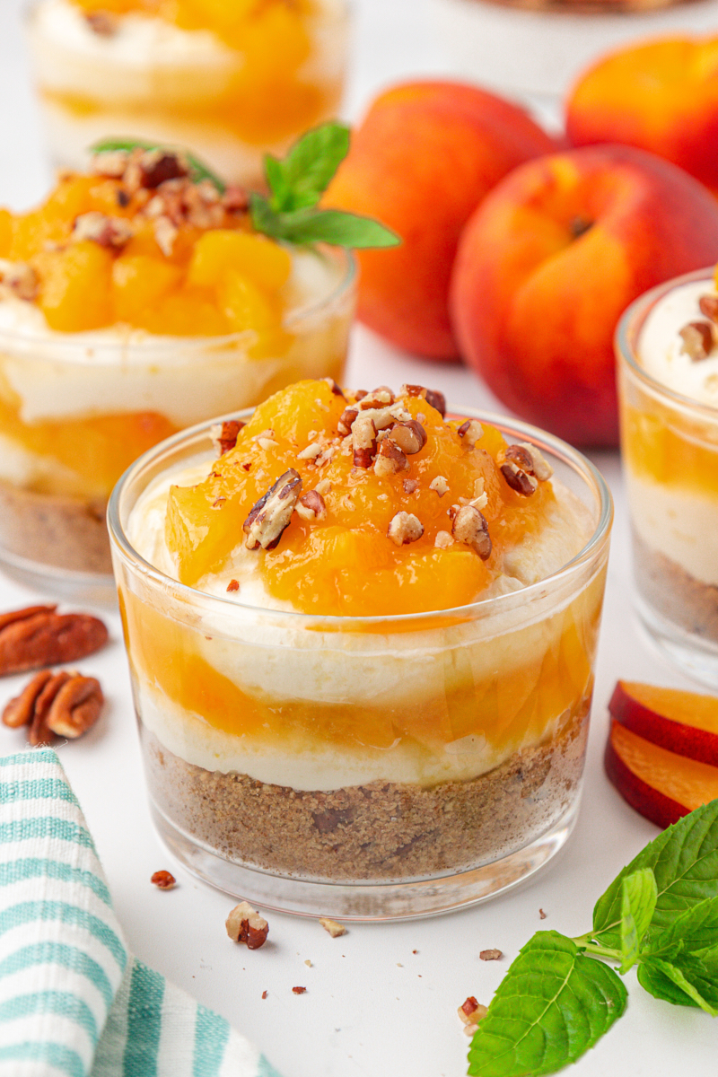 no-bake peach cheesecake jars with layers of graham cracker crust, cheesecake filling, and peach compote