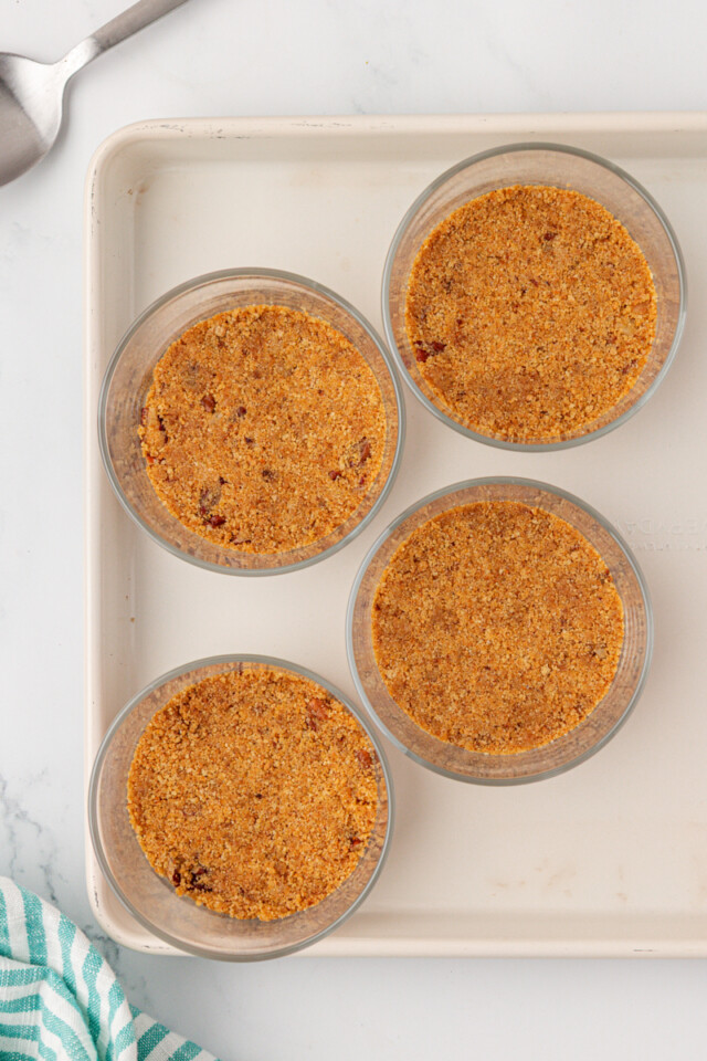 overhead view of graham cracker crust mixture divided between four dessert jars