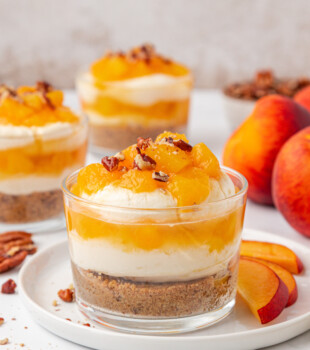 peach cheesecake jars with layers of graham cracker crust, no-bake cheesecake filling, and peach compote