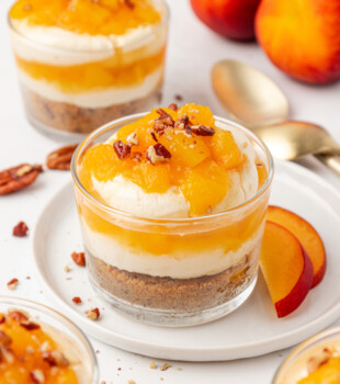 no-bake peach cheesecake jar with layers of graham cracker crust, creamy cheesecake filling, and fresh peach compote