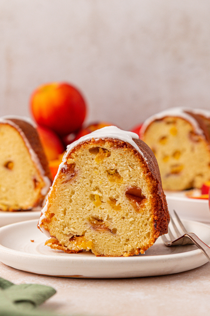 a slice of peach pound cake filled with fresh peaches and topped with an almond glaze