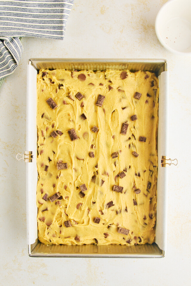chocolate chunk blondie batter spread in a 9x13 pan ready to go into the oven