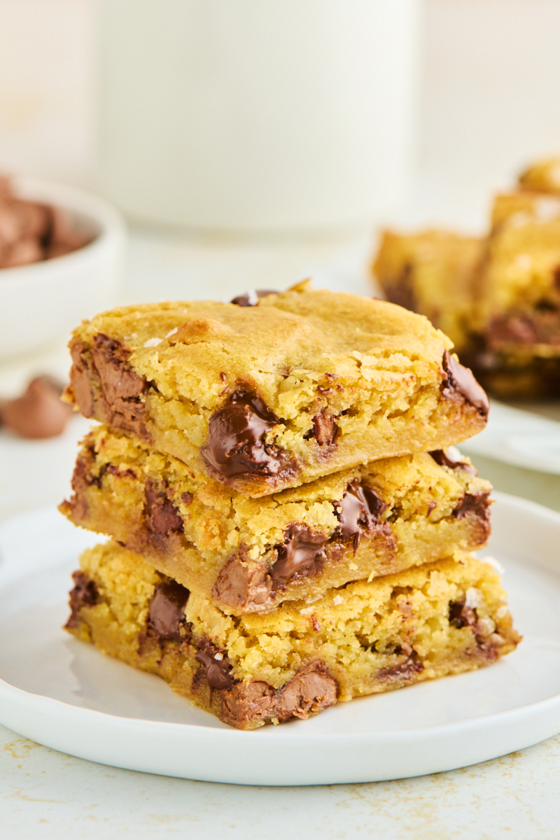 stack of three chocolate chunk blondies made with two kinds of chocolate and topped with flaky salt