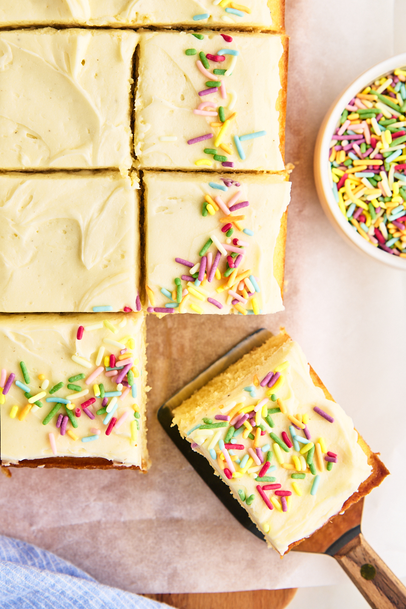 partially sliced vanilla sheet cake topped with vanilla frosting