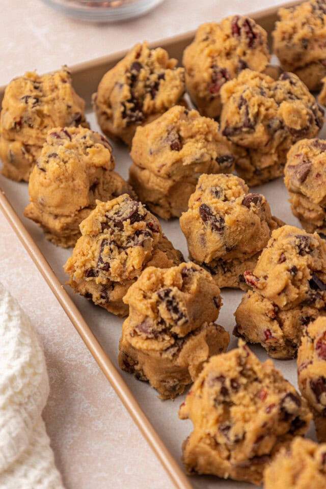 loaded chocolate chip cookie dough shaped into rough, tall mounds on a baking sheet before chilling