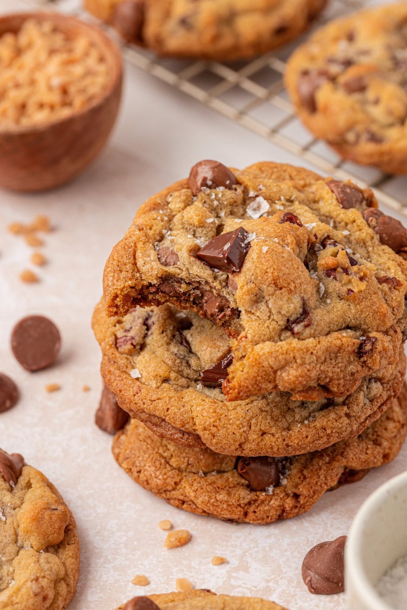 stack of three bakery-style loaded chocolate chip cookies with a bite missing from the top cookie