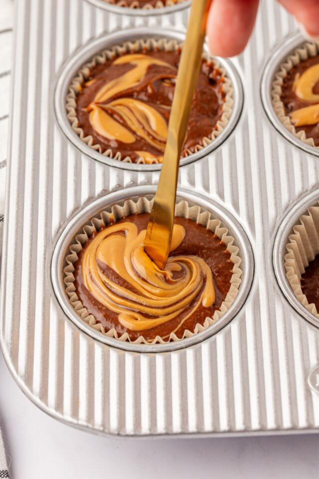 warmed peanut butter being swirled into chocolate muffin batter