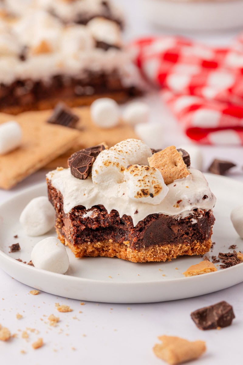a s'mores brownie featuring a graham cracker crust, fudgy brownie, and marshmallow frosting