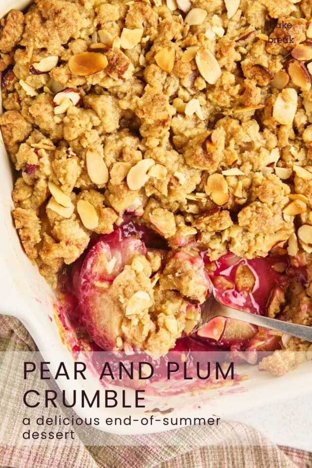 a spoonful of pear and plum crumble resting in the pan with the remaining crumble; text overlay "pear and plum crumble - a delicous end-of-summer dessert"