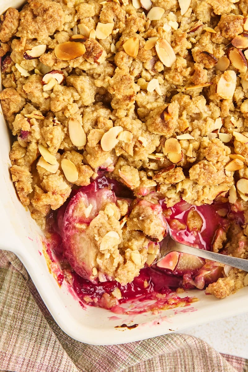 overhead view of a large spoonful of pear and plum crumble resting in the dish with the remaining crumble