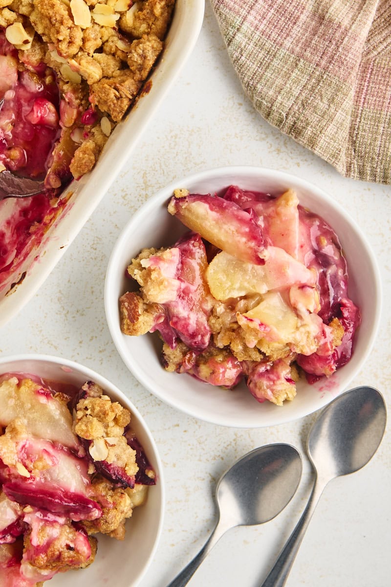 bowls of pear and plum crumble alongside remaining crumble