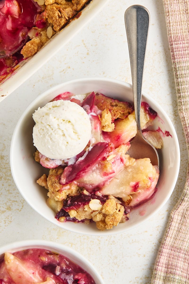overhead view of a serving of pear and plum crumble with a buttery cinnamon-almond topping served with a scoop of ice cream
