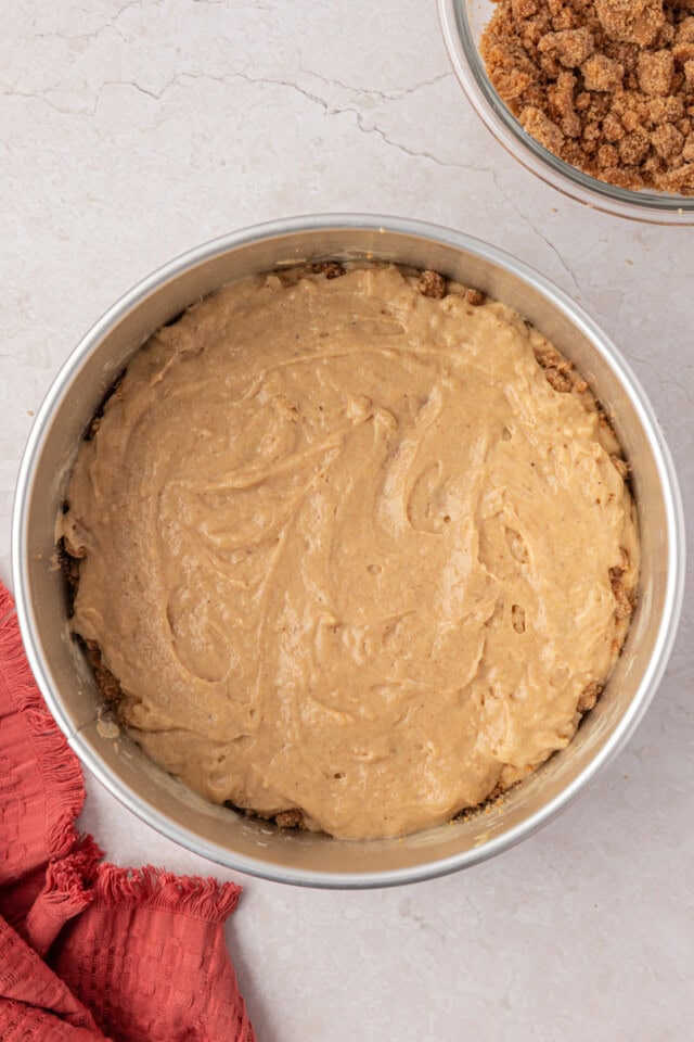 top layer of cinnamon muffin cake batter spread over layers of streusel and batter