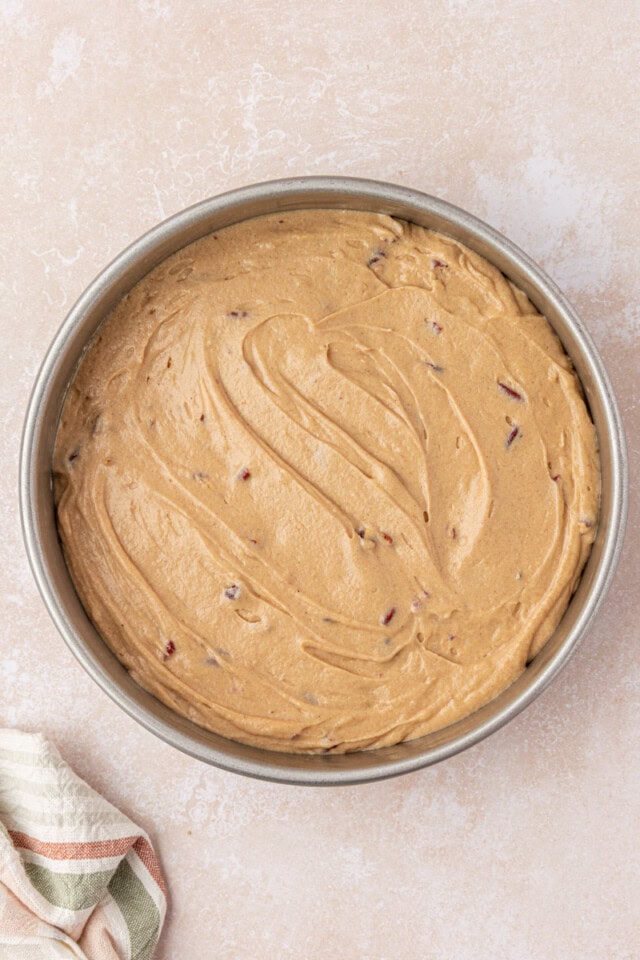 maple cake batter spread in a round cake pan before going into the oven