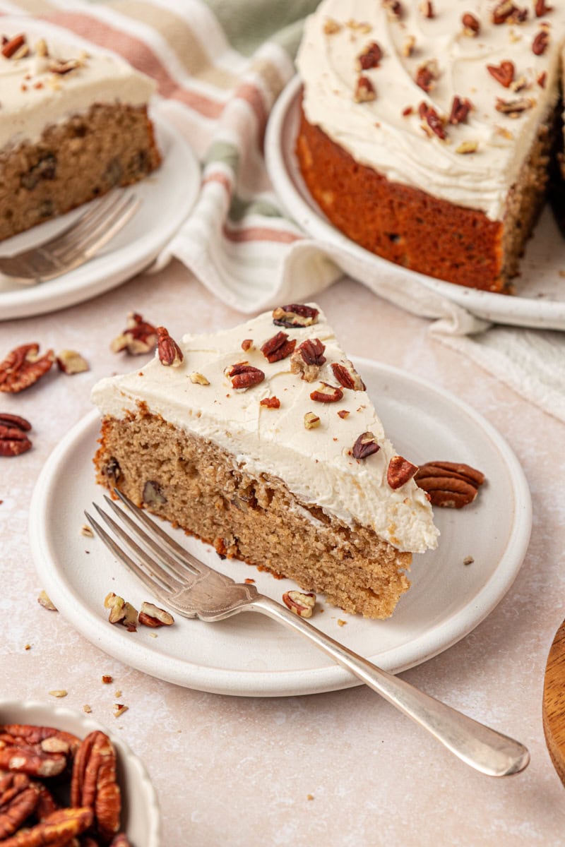 a slice of maple cake topped with maple frosting and toasted pecans