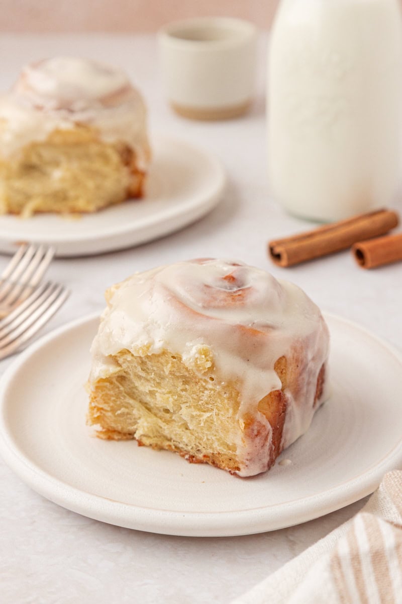 a cinnamon roll topped with cream cheese frosting and served on a white plate