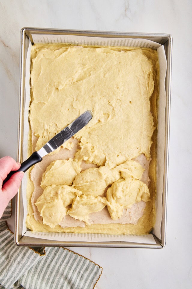 top layer of coffee cake batter being spread over cinnamon cream cheese filling