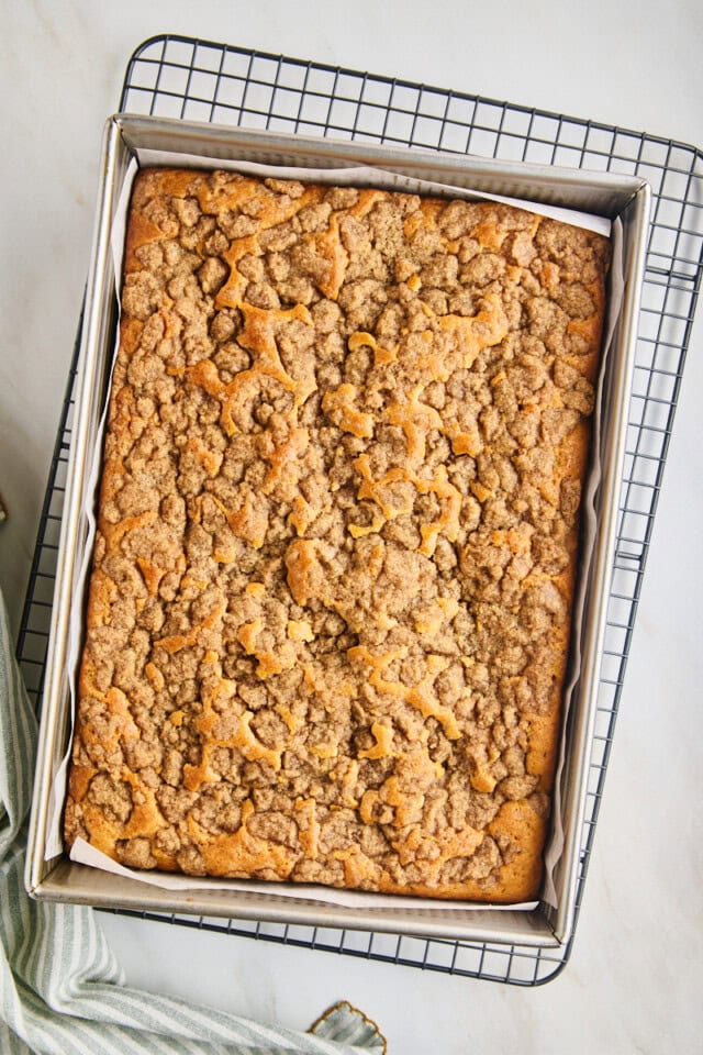 freshly baked cinnamon cream cheese coffee cake in a 9x13 pan set on a wire rack to cool