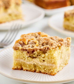 slice of coffee cake with a layer of cinnamon cream cheese filling and topped with buttery crumb