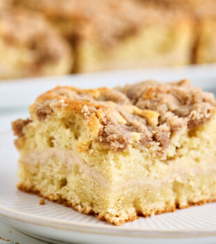 close-up view of a slice of cinnamon cream cheese coffee cake with a cinnamon cream cheese filling and buttery crumb topping