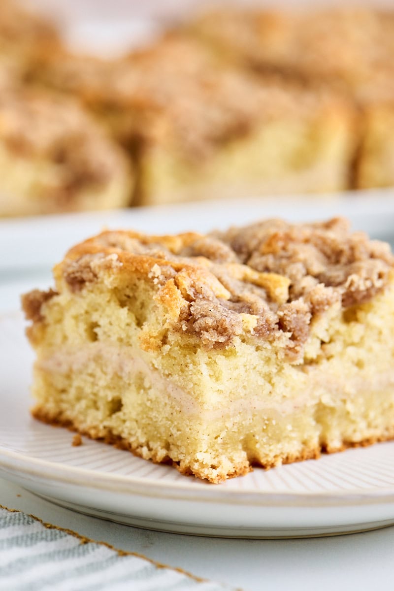 close-up view of a slice of cinnamon cream cheese coffee cake with a cinnamon cream cheese filling and buttery crumb topping