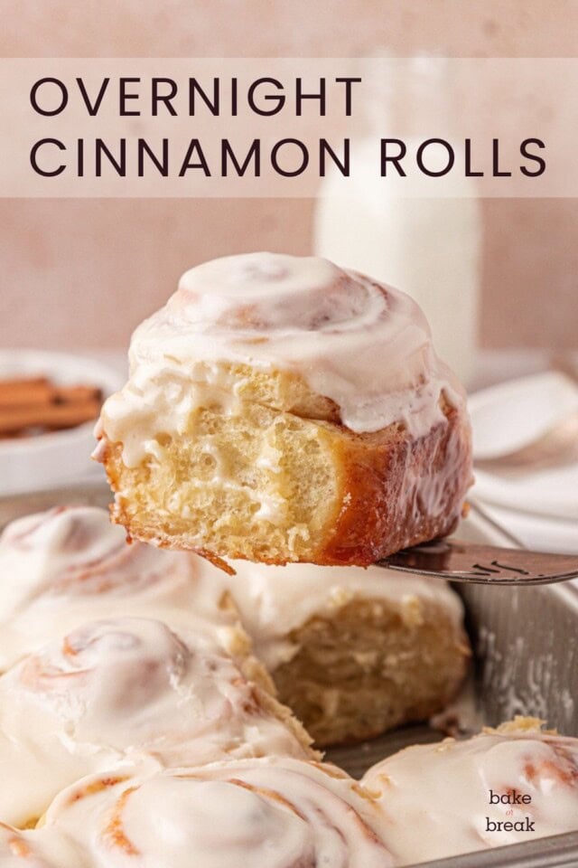a frosted cinnamon roll being lifted from the pan; text overlay "overnight cinnamon rolls"