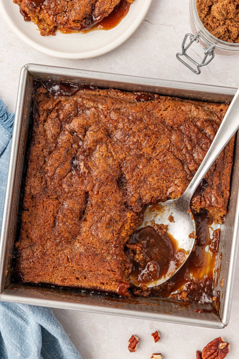 overhead view of butterscotch pudding cake in a square baking pan with a scoop removed