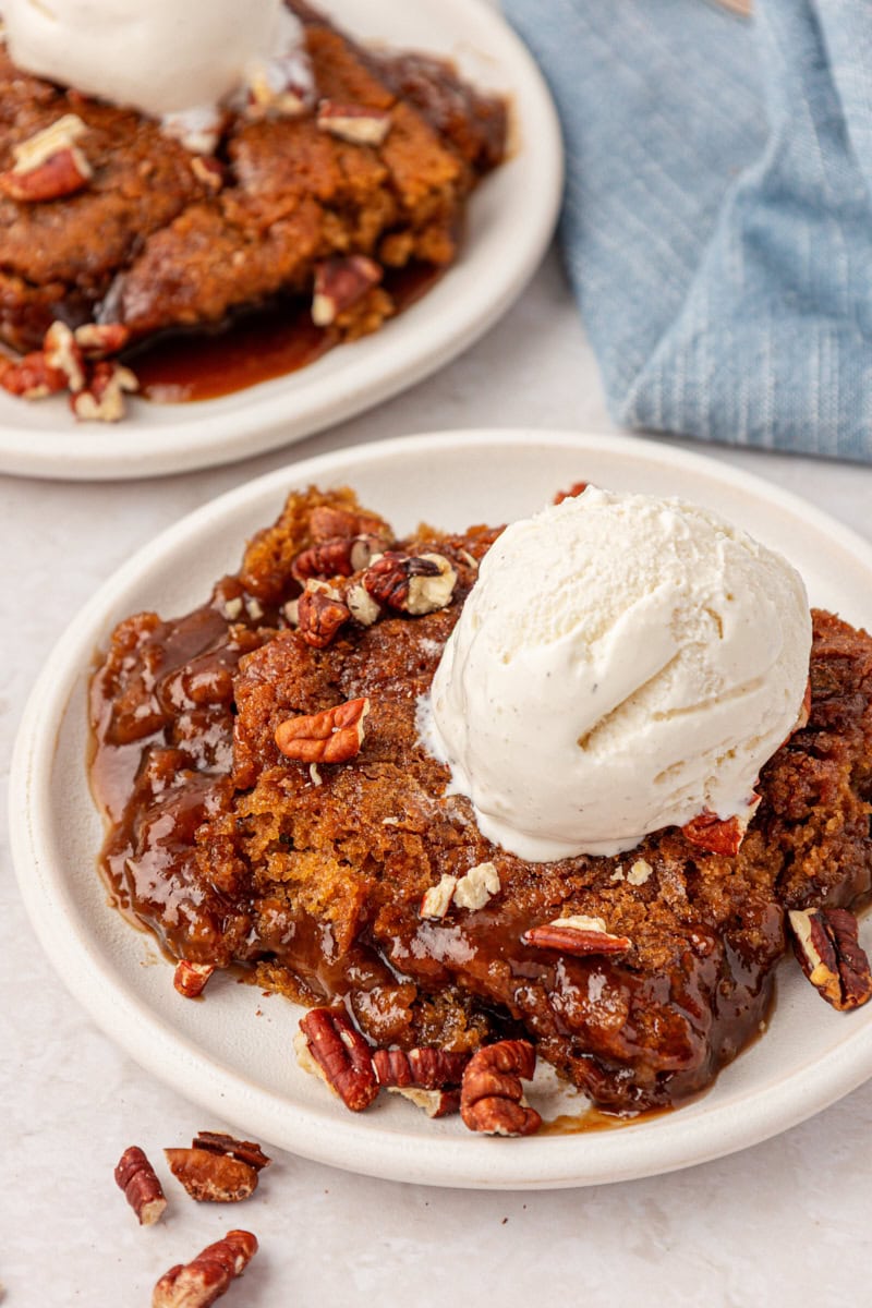a serving of self-saucing butterscotch pudding cake topped with ice cream and toasted pecans