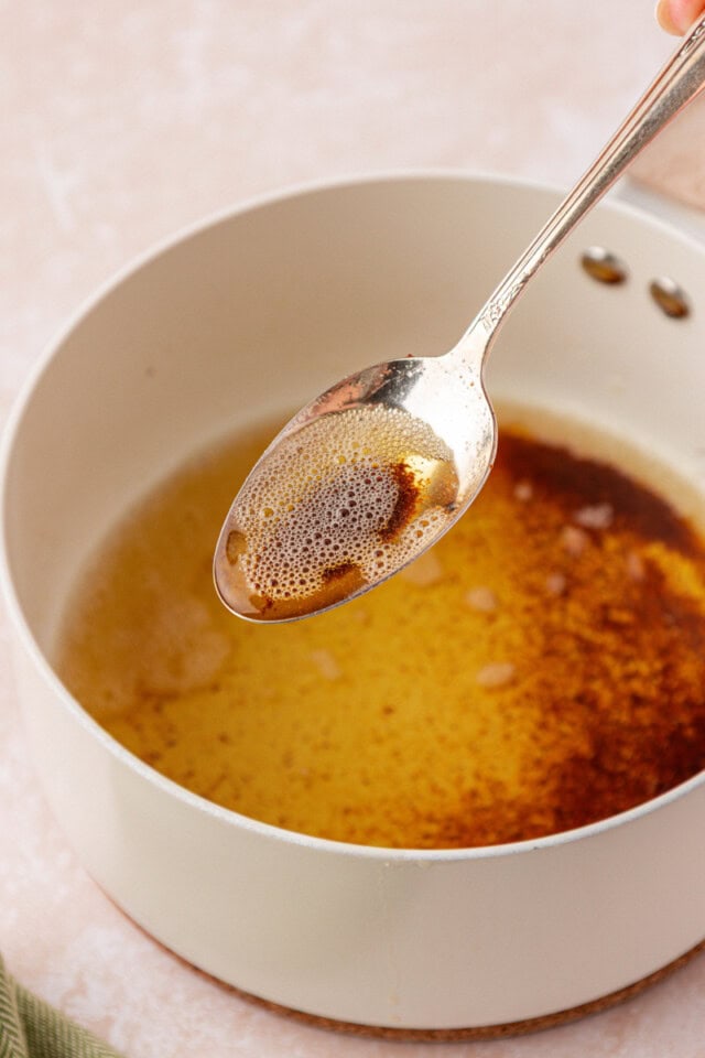 a spoonful of browned butter held over a saucepan