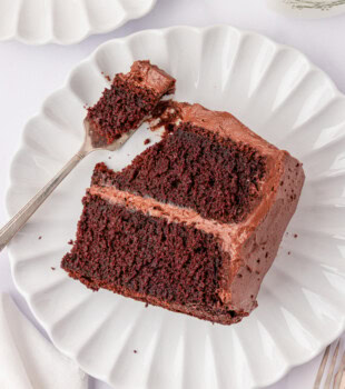 overhead view of a slice of devil's food cake with chocolate buttercream on a white plate